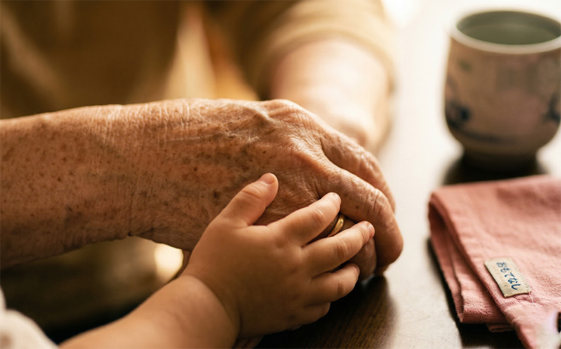 祖父と孫の手を優しく握り合うクローズアップ