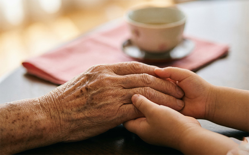 祖父と孫の手を優しく握り合うクローズアップ