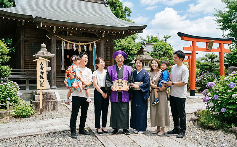 古希御祝で神社の前に集まった三世代家族の集合写真