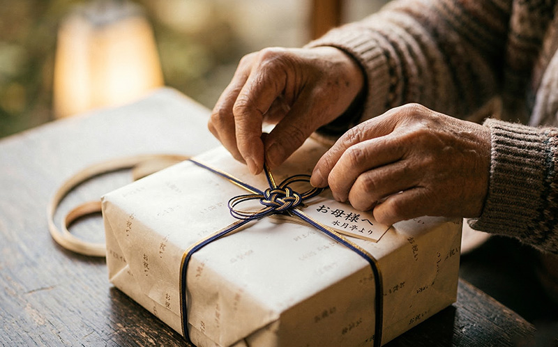 贈り物の水引を丁寧にほどく高齢者の手元のクローズアップ