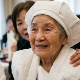 白いちゃんちゃんこ姿の99歳女性が感動の涙を浮かべるポートレート