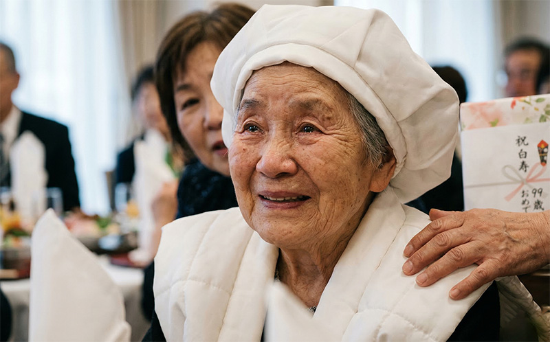 白いちゃんちゃんこ姿の99歳女性が感動の涙を浮かべるポートレート