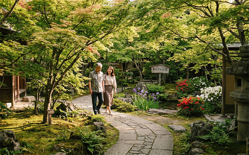 緑の日本庭園を60代男性と家族がゆっくり散歩する午後の風景
