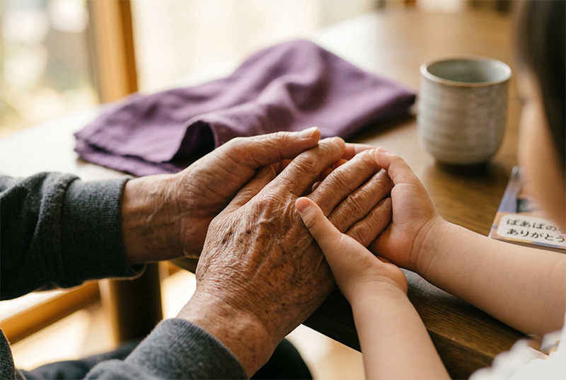 祖父の手を優しく握る孫の手のクローズアップ