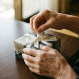白いリボンのプレゼントを丁寧に開ける99歳の手元クローズアップ