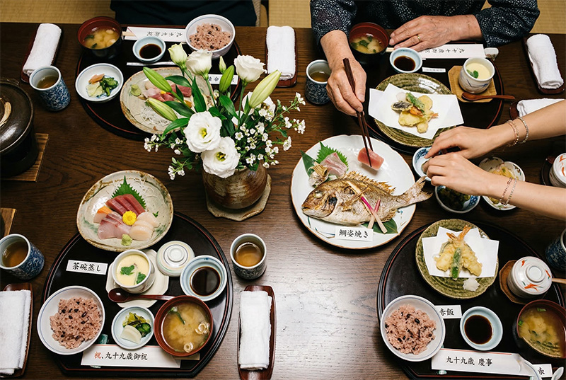 白寿祝いの懐石料理を真上から撮影した鯛の姿焼きと白い花