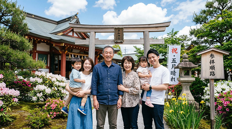 神社の前で退職祝いの三世代家族集合写真