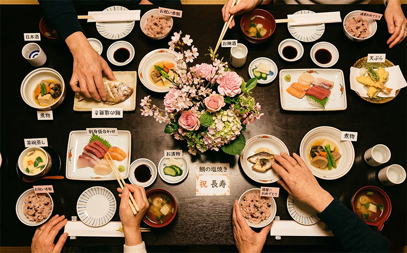 長寿祝いの懐石料理を真上から撮影したピンクの花と鯛の姿焼き